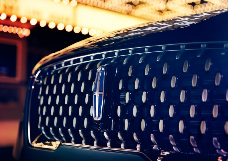 The Corsair Grand Touring grille shows floating chrome ovals that catch the glowing light of a theater marquee and frame the distinctive Lincoln Star | Loveland Lincoln in Loveland CO