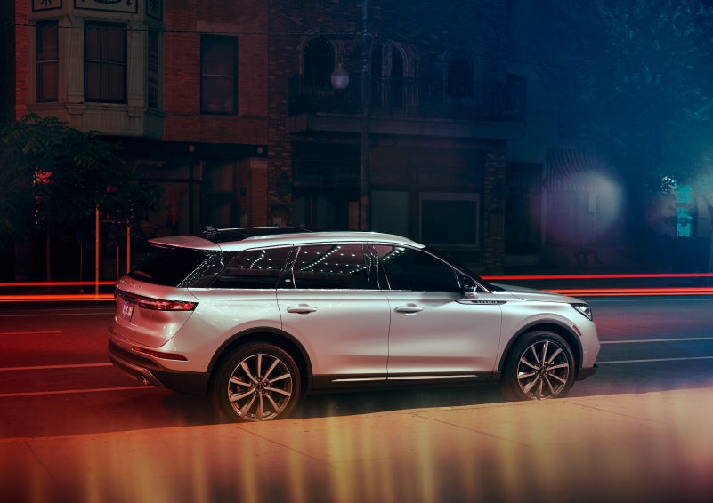A 2022 Lincoln Corsair SUV is parked near a theater at night as the bright lights of a marquee dance across the dark windows and curvature of the body | Loveland Lincoln in Loveland CO