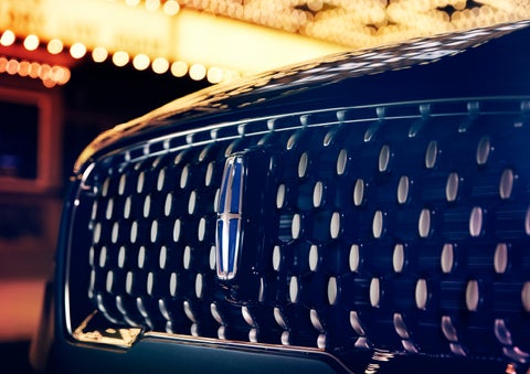 The Corsair Grand Touring grille shows floating chrome ovals that catch the glowing light of a theater marquee and frame the distinctive Lincoln Star | Loveland Lincoln in Loveland CO