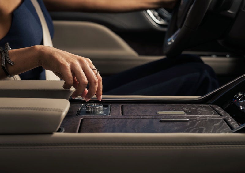 A hand is about to turn the Lincoln Drive Modes knob on the center console.