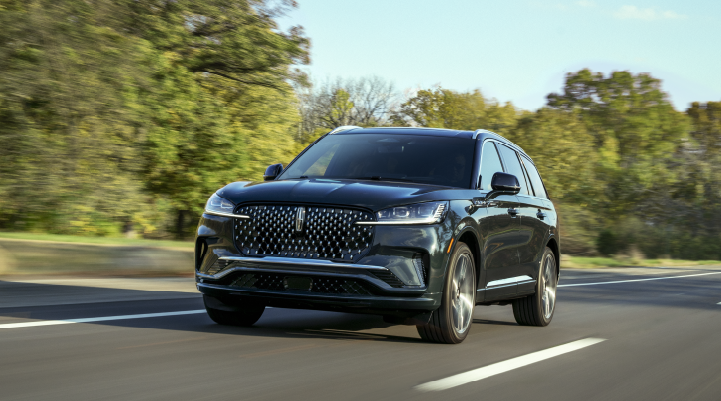 A 2025 Lincoln Black Label Aviator® SUV is being driven down a road lined with trees. | Loveland Lincoln in Loveland CO
