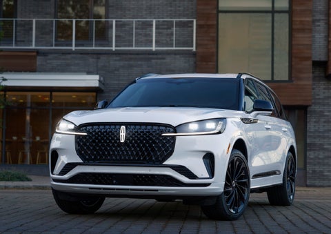 A 2026 Lincoln Aviator® Reserve model is shown with the available Jet Appearance Package parked near a restaurant. | Loveland Lincoln in Loveland CO