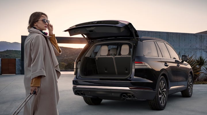 A woman approaches a 2026 Lincoln Aviator® SUV with its rear liftgate open. | Loveland Lincoln in Loveland CO