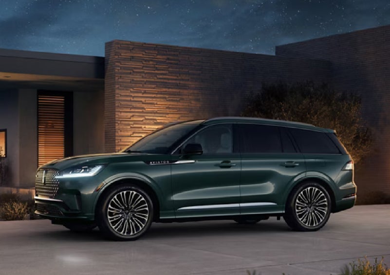 A green 2027 Lincoln Aviator® SUV is parked outside a contemporary home. | Loveland Lincoln in Loveland CO
