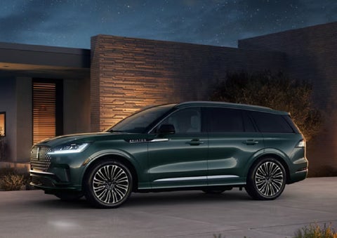 A green 2027 Lincoln Aviator® SUV is parked outside a contemporary home. | Loveland Lincoln in Loveland CO