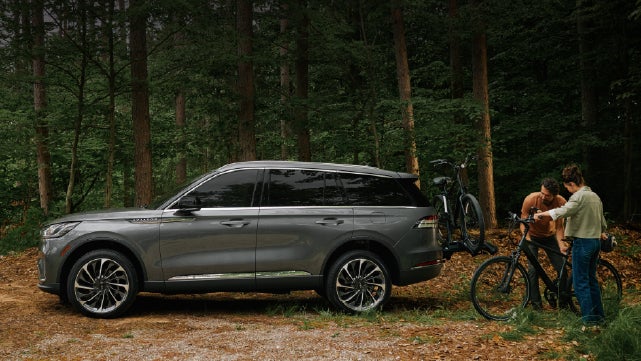 A father and son load e-bikes on a bike rack attached to a 2027 Lincoln Aviator® SUV. | Loveland Lincoln in Loveland CO